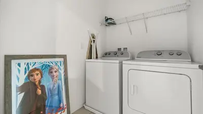 a laundry room with a washer and a picture at 6BR Luxury Home with Private Pool and BBQ in Kissimmee