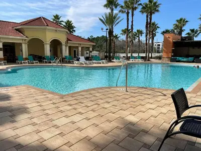 a large swimming pool with chairs and palm trees at The Point, Lux Apartment 4 min from Universal in Orlando