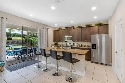 a kitchen with a refrigerator and a counter with bar stools at 7462 Themed Villa 6BD - Pool Spa-Game room in Orlando