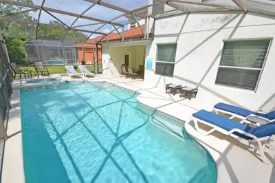 a swimming pool with two chairs and a house at Mariel Oasis home in Kissimmee
