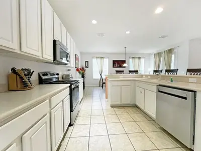 a large white kitchen with white cabinets and appliances at Mariel Oasis home in Kissimmee