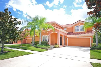 a large orange house with palm trees and a driveway at Summer Sparkle home in Kissimmee
