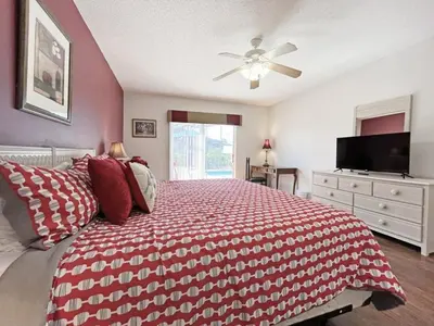 a bedroom with a red and white bed with a ceiling fan at Ainsdale Haven home in Kissimmee