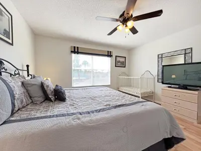 a bedroom with a bed with a ceiling fan and a flat screen tv at Ainsdale Haven home in Kissimmee