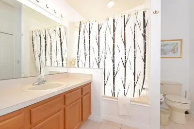 a bathroom with a sink and a toilet and a mirror at Sweet Magnolia home in Orlando