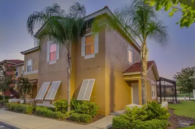 a house with palm trees in front of it at Villa Azul townhouse in Kissimmee
