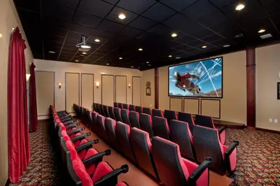 a cinema room with red chairs and a screen at California Palms condo in Kissimmee