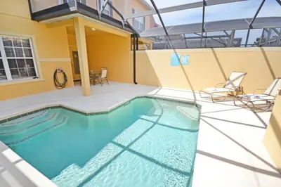 a swimming pool with two chairs and a building at Candy Palm townhouse in Kissimmee