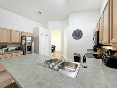 a kitchen with a sink and a clock on the wall at Sunshine Villa villa in Kissimmee