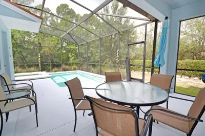 a patio with a table and chairs and a swimming pool at Bamboo Palm home in Kissimmee