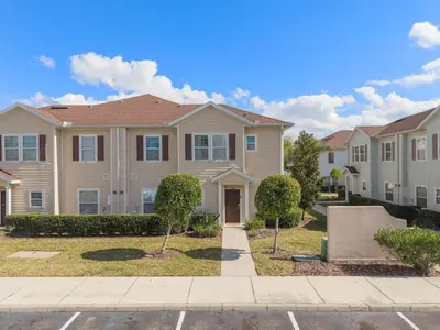 a large house with bushes in front of it at Beautiful & Cozy 4bd Home, Gated Community in Kissimmee
