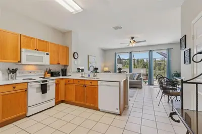 a kitchen with white appliances and a living room at Veteran Owned 3bdr/3 bath Townhouse w/WiFi 3mi to Disney - Winter/Spring Specials in Kissimmee