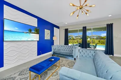 a living room with a blue couch and a view of the ocean at Alluring Home Near Disney With Themed, Media And Game Room With Waterpark & Resort Access At Encore Resorts Reunion - 232Au in Kissimmee