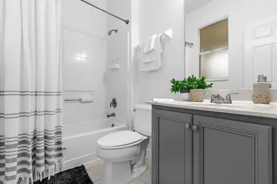 a white bathroom with a toilet and a sink at Hidden gem! Gorgeous villa next to Disney in Kissimmee