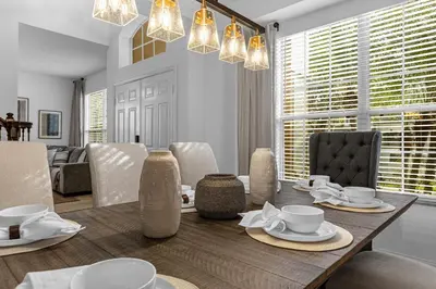 a dining room with a wooden table with plates and cups at Hidden gem! Gorgeous villa next to Disney in Kissimmee