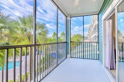 a balcony with a view of a pool and palm trees at 3BR Condo with Pool - Near Disney in Orlando