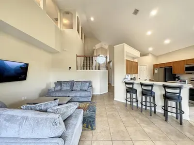 a living room with a couch and chairs and a kitchen at Luxury 6BD 3,5BA Pool Home in Windsor Palms Resort villa in Kissimmee