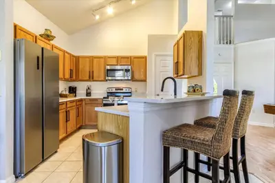 a kitchen with wooden cabinets and a stainless steel refrigerator at Large Home-Private Pool, Spa, and Pet Friendly Sleeps 12 in Orlando