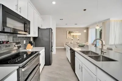 a kitchen with white cabinets and a black refrigerator at Amazing Story Lake Town Home With Pool townhouse in Kissimmee