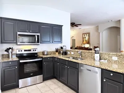 a kitchen with black cabinets and stainless steel appliances at Lovely Lakeside 4-Bed Pool Home at Villa Sol-3125 home in Kissimmee