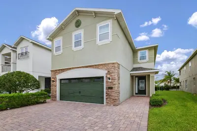 a large white house with a garage at Inviting Home Near Disney With Private Pool And Waterpark & Resort Access At Encore Resorts Reunion - 7578Mr in Kissimmee
