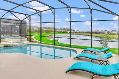 a swimming pool with blue chairs and a large glass house at 6BR Luxury Home w Pool Hot Tub and Games room in Kissimmee