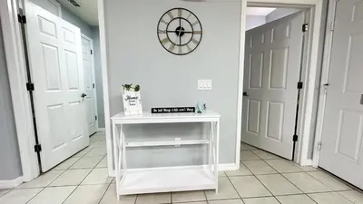 a hallway with a white table and a clock on the wall at Amazing 3 Bdrm At Encantada- 6 miles from Disney in Kissimmee