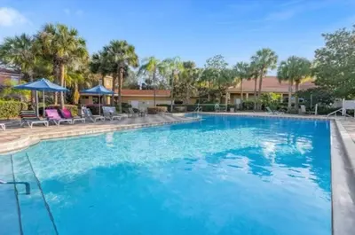 a large blue swimming pool with chairs and umbrellas at Cozy 3Bdrms At Encantada- 6 miles from Disney in Kissimmee