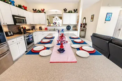 a kitchen with a long table with red and white plates at Family Friendly Emerald Island Resort Vacation Home with Private Pool and Spa Near Disney in Kissimmee