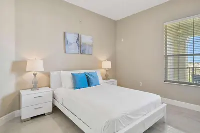 a white bedroom with a white bed with blue pillows at 4804 Cayview Avenue 401 in Orlando