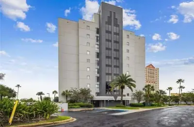a large white building with palm trees in front of it at Remodeled 2BD/2BA Condo mins from Universal Studio in Orlando
