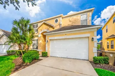 a house with a garage and a palm tree at Emerald Island Escape- Pool and spa in Kissimmee