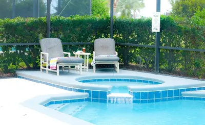 a swimming pool with two chairs and a table in the middle at Luxury 5 Bedroom Villa with Secluded Pool/Spa in Glenbrook community near Orlando in Orlando