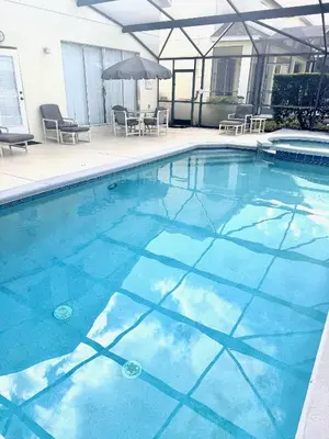 a swimming pool with blue water and chairs and an umbrella at Luxury 5 Bedroom Villa with Secluded Pool/Spa in Glenbrook community near Orlando in Orlando