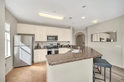 a kitchen with white cabinets and a granite counter top at Condo w Pool, Games Room - Pet Friendly in Orlando
