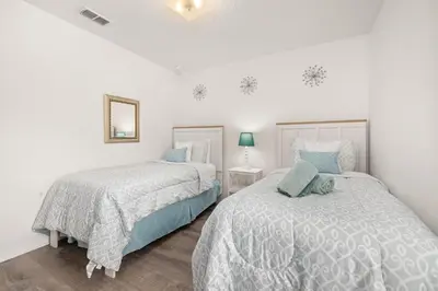 two beds in a bedroom with white walls and blue pillows at #196-Fantastic 6 bed villa with own private pool and spa with no rear neighbors in Orlando