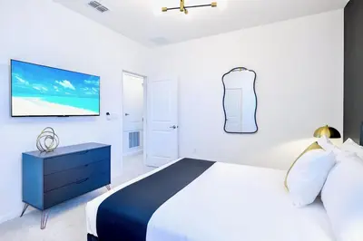 a bedroom with a bed and a flat screen tv at 8BR Resort Home with Games Room and BBQ in Kissimmee