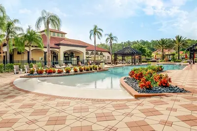 a pool at a resort with flowers in a courtyard at 8BR Resort Home with Games Room and BBQ in Kissimmee