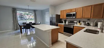 a kitchen with wooden cabinets and a dining room with a table at Shvpc3 - Paradise Cay #3 - 3 Bed 25 Baths Townhome in Kissimmee