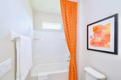 a bathroom with an orange shower curtain next to a tub at 15BR Mansion Home with Pool & Hot Tub-near Disney in Kissimmee