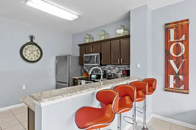 a kitchen with orange chairs at a counter at The Wish House, just miles from Disney World in Orlando