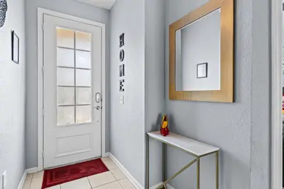 a hallway with a door and a table and a mirror at The Wish House, just miles from Disney World in Orlando