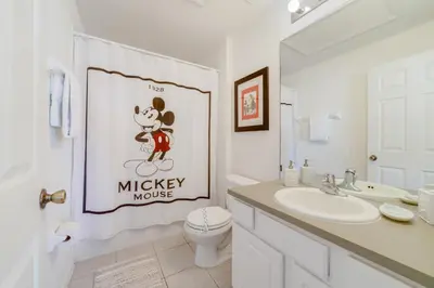 a bathroom with a mickey mouse sign on the shower curtain at Windsor Hills Townhome in Orlando