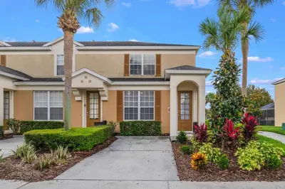 a house with palm trees and a sidewalk at Windsor Hills Townhome in Orlando