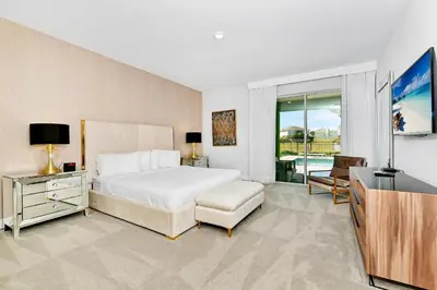 a bedroom with a white bed and a television at Elite Home Near Disney With Theater Room, Game Room And Private Pool With Water Park Access At Encore Resorts Reunion - 200Au in Kissimmee