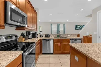 a kitchen with stainless steel appliances and wooden cabinets at 541 Villa- 7BD Dream Home - Private PoolSpa in Orlando