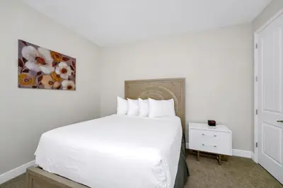 a bedroom with a white bed and a painting on the wall at Lovely Home Near Disney With Private Pool, Water Park & Resort Access At Encore Resort Reunion - 7423Mr in Kissimmee