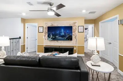a living room with a black leather couch and a tv at Luxury 9BR Villa @ Storey Lake Resort Near Disney in Kissimmee