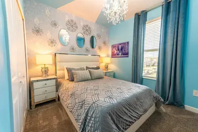 a bedroom with a bed with blue walls and a chandelier at 6BR Disney Oasis with Pool, Game Room and Resort in Kissimmee