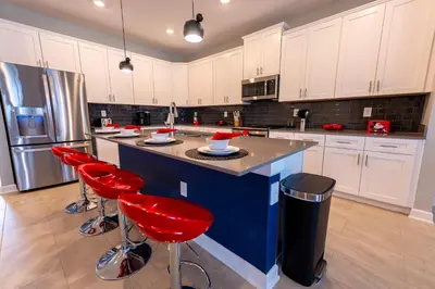 a kitchen with a blue island with red bar stools at 6BR Disney Oasis with Pool, Game Room and Resort in Kissimmee